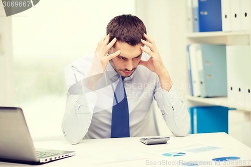 Image of stressed businessman with laptop and documents