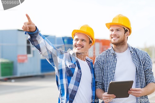 Image of smiling builders in hardhats with tablet pc