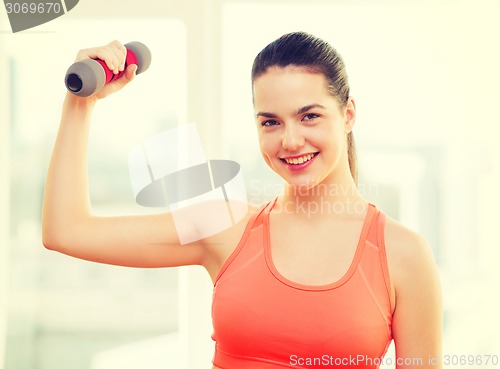 Image of smiling teenage girl exercising with dumbbell