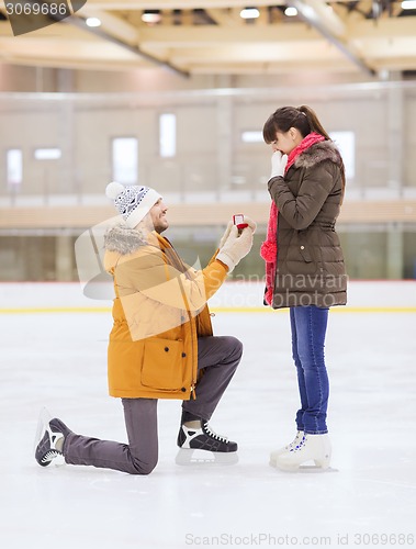 Image of happy couple with engagement ring on skating rink