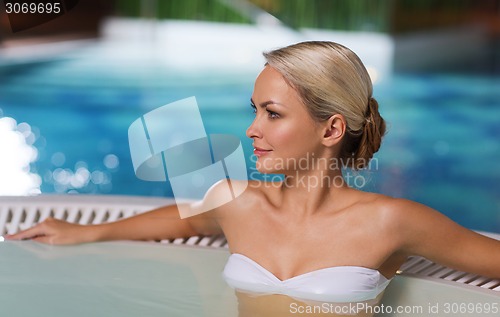 Image of happy woman sitting in jacuzzi at poolside