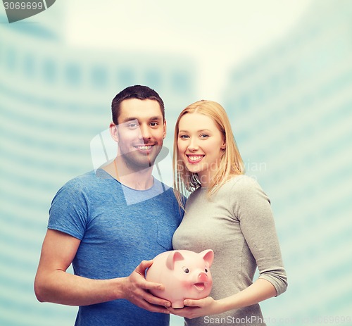 Image of smiling couple holding big piggy bank