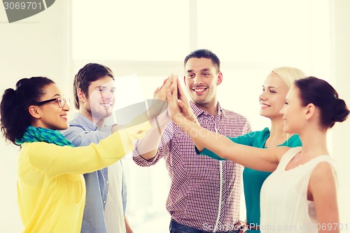 Image of creative team doing high five gesture in office