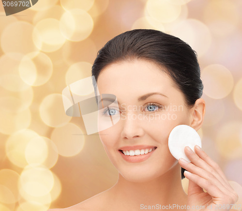 Image of smiling woman cleaning face skin with cotton pad