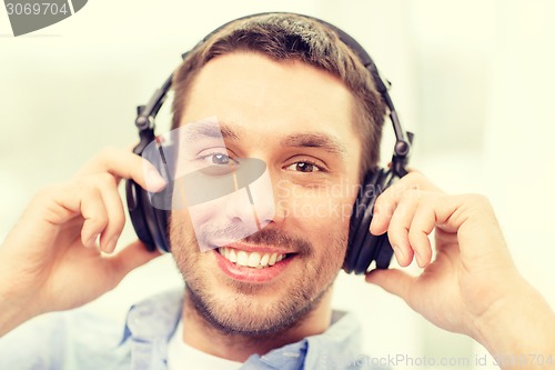 Image of smiling young man in headphones at home