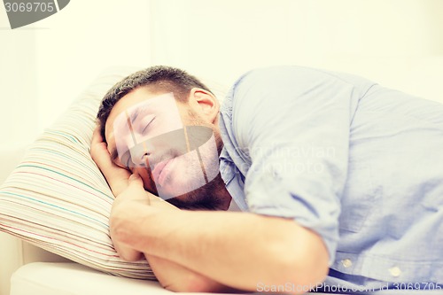 Image of calm young man lying on sofa at home