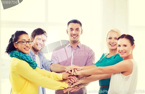 Image of team with hands on top of each other in office