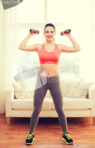 Image of smiling teenage girl exercising with dumbbells