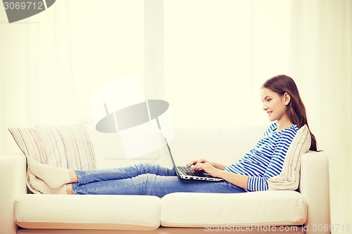 Image of smiling teenage girl with laptop computer at home