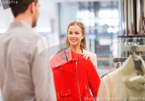 Image of happy young couple choosing clothes in mall