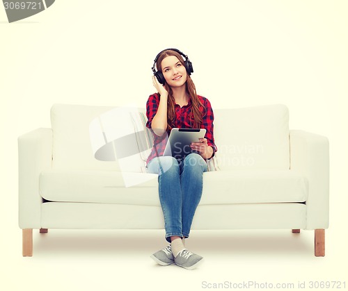 Image of girl sitting on sofa with headphones and tablet pc