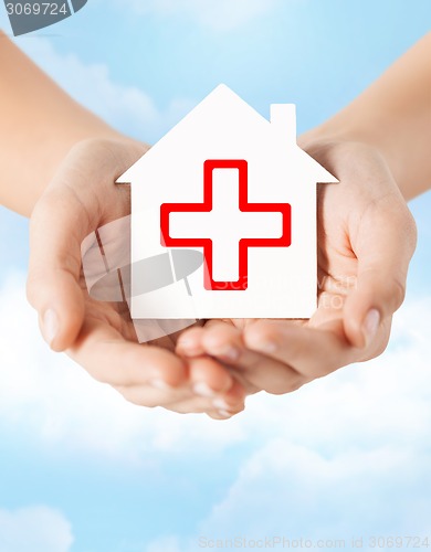 Image of hands holding paper house with red cross