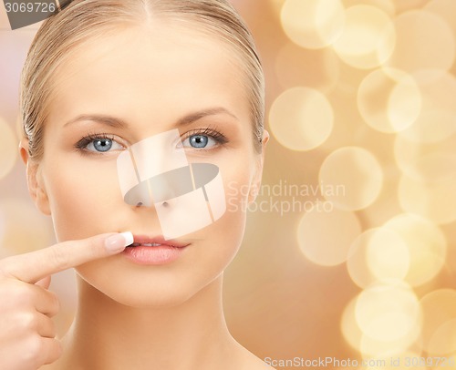 Image of beautiful young woman pointing finger to her lips