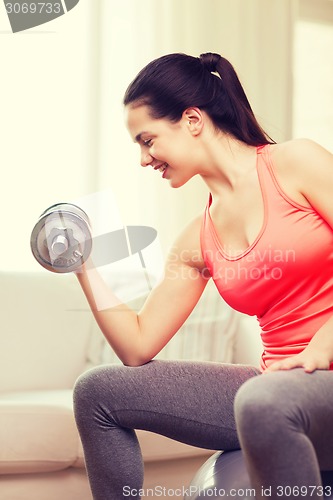 Image of smiling girl exercising with dumbbells