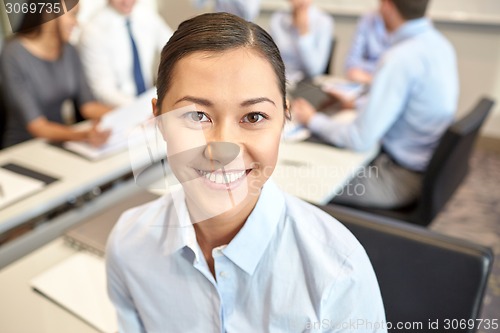 Image of group of smiling businesspeople meeting in office