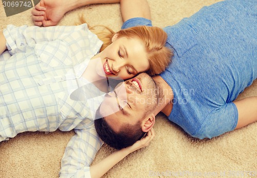 Image of smiling happy couple lying on floor at home