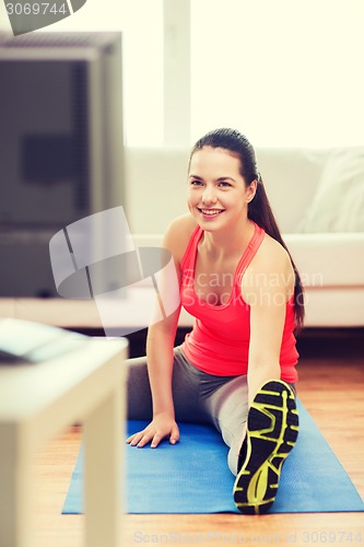 Image of smiling teenage girl streching on floor at home