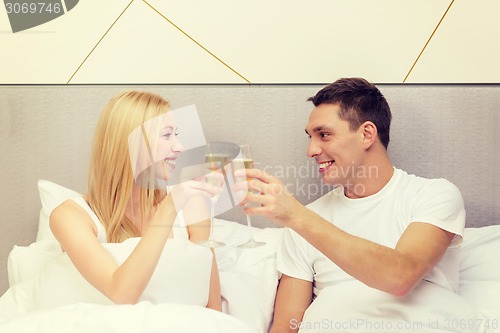 Image of smiling couple with champagne glasses in bed