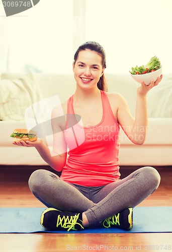 Image of smiling teenager with green salad and hamburger