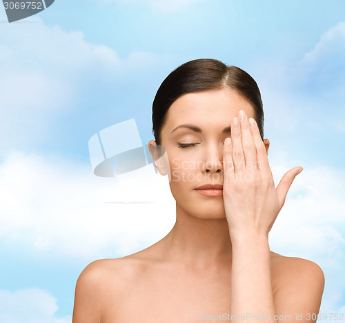 Image of smiling young woman covering face with hand
