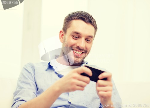 Image of smiling man with smartphone at home