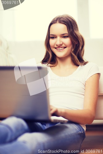 Image of smiling teenage girl with laptop computer at home