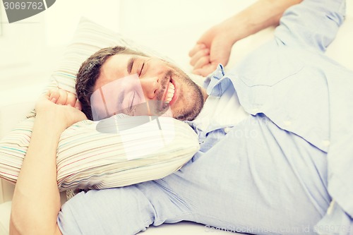 Image of smiling young man lying on sofa at home