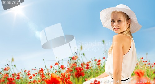 Image of smiling young woman in straw hat on poppy field
