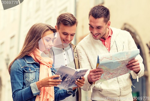 Image of group of smiling friends with city guide and map