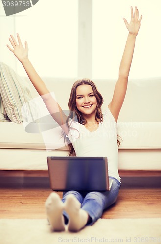 Image of smiling teenage girl with laptop computer at home
