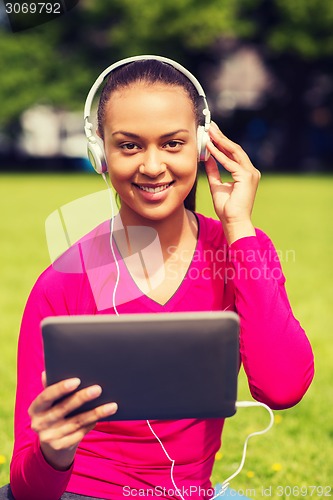 Image of smiling woman with tablet pc outdoors