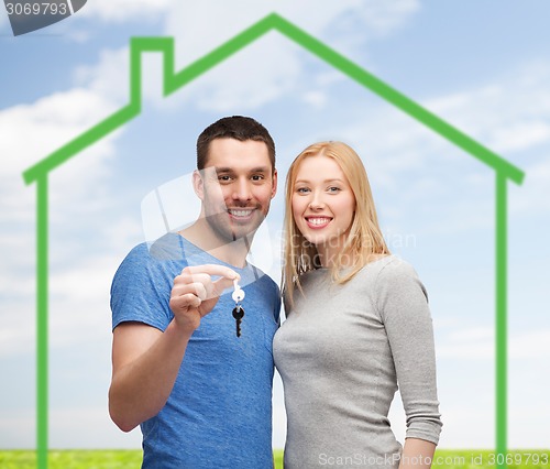 Image of smiling couple holding key over green house