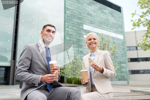 Image of smiling businessmen with paper cups outdoors