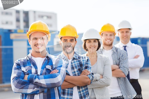 Image of group of smiling builders in hardhats outdoors