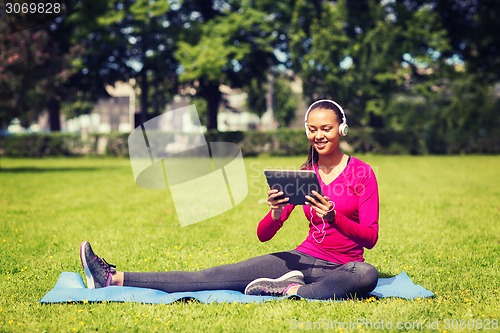 Image of smiling woman with tablet pc outdoors