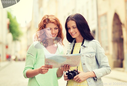 Image of smiling teenage girls with map and camera