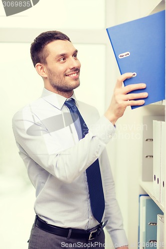 Image of handsome businessman picking folder at office