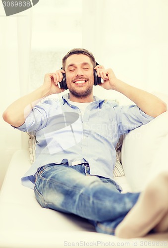 Image of smiling young man in headphones at home
