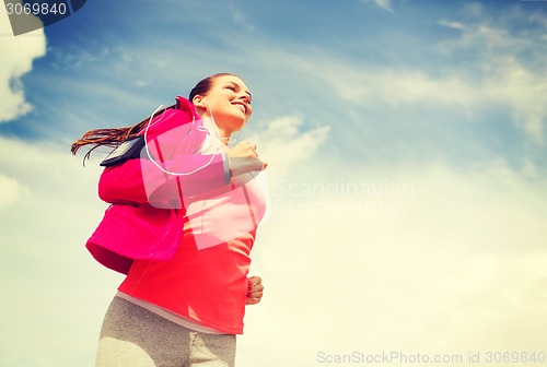 Image of smiling young woman running outdoors