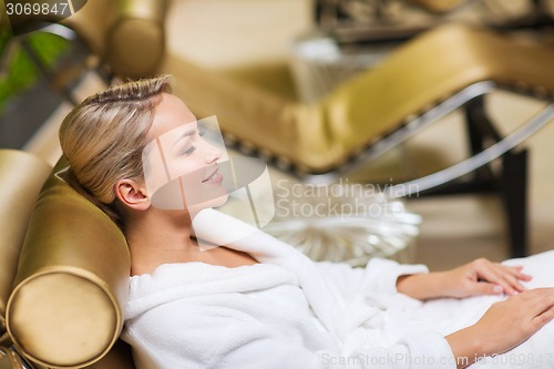 Image of beautiful young woman sitting in bath robe at spa