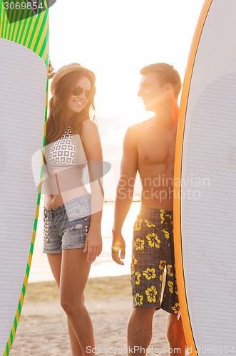 Image of smiling couple in sunglasses with surfs on beach