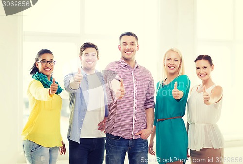 Image of happy creative team showing thumbs up in office