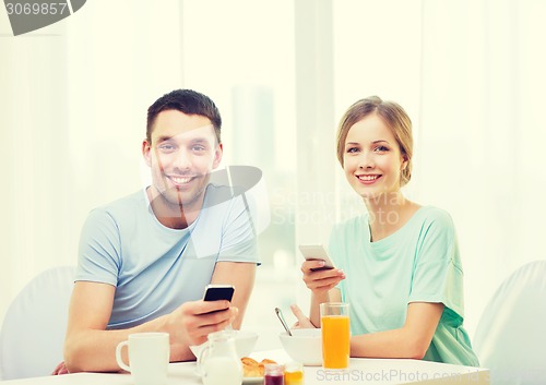 Image of smiling couple with smartphones reading news