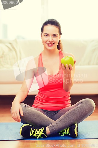 Image of smiling teenage girl with green apple at home