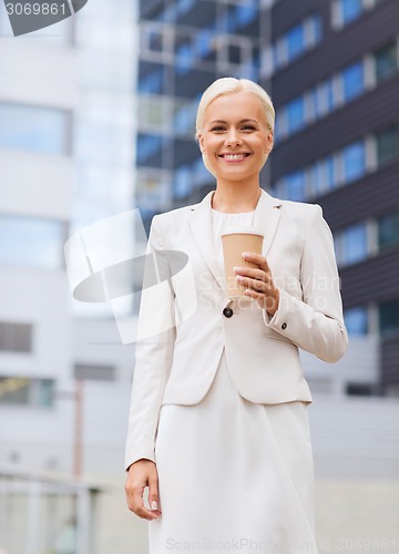 Image of smiling businesswoman with paper cup outdoors