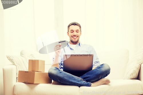 Image of man with laptop, credit card and cardboard boxes