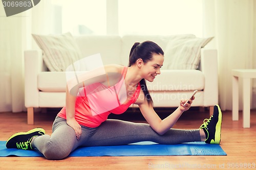 Image of smiling teenage girl streching on floor at home