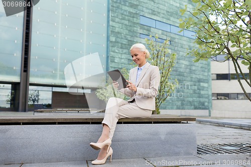 Image of smiling businesswoman with tablet pc outdoors