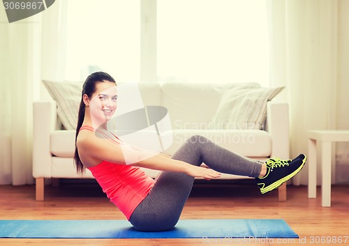 Image of smiling girl doing exercise on floor at home