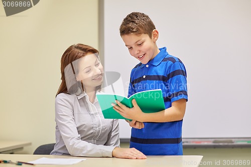 Image of school boy with notebook and teacher in classroom